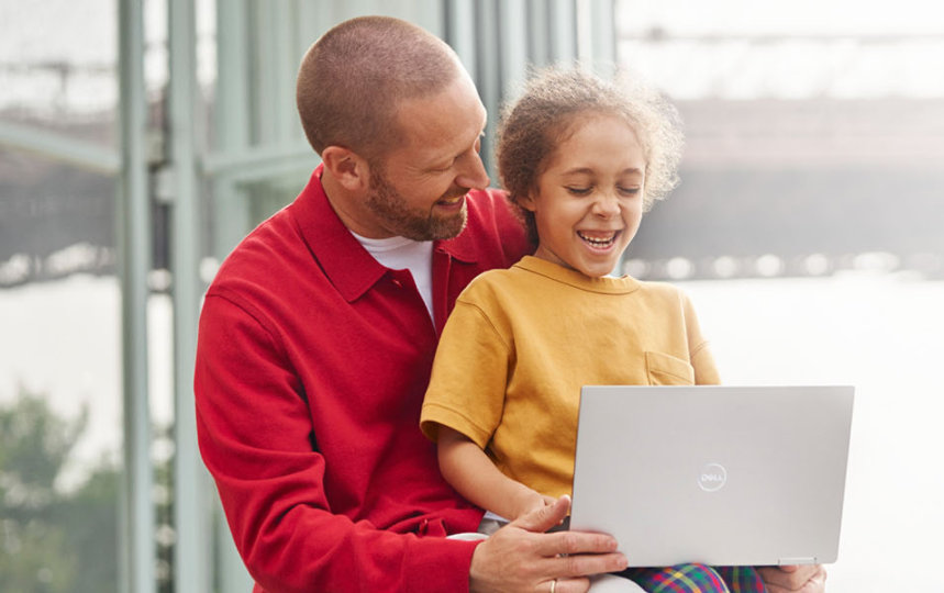 Un bărbat și o fetiță râd și se uită la laptop