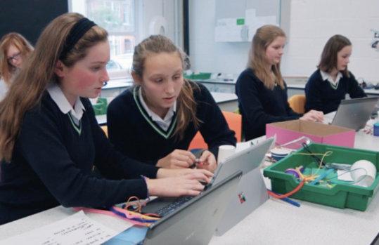 Students work together in front of a laptop.