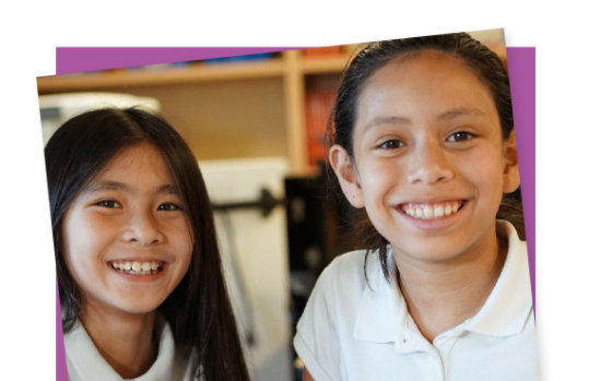 Two young girls hold up a hardware chip that works with MakeCode.