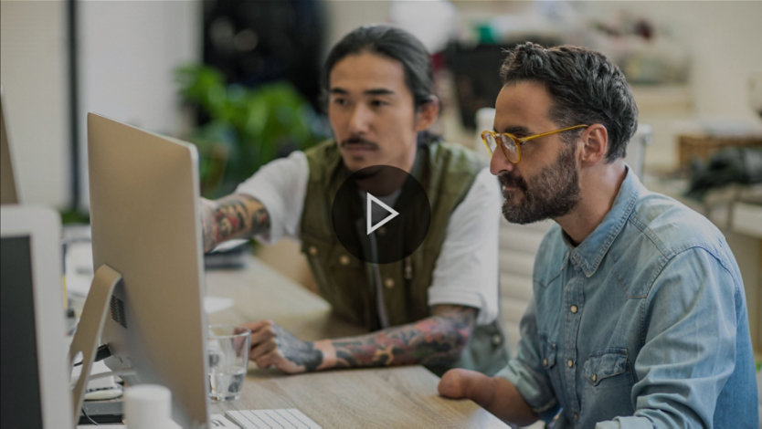 Two people working together at a computer monitor