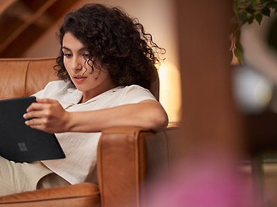 A woman lying in a sofa and using her tablet