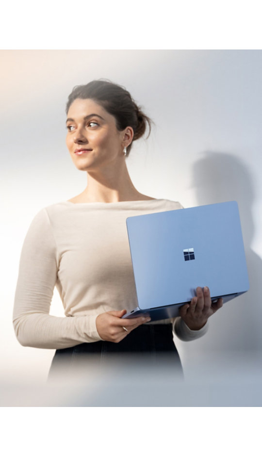 Surface Laptop 13.8 インチ (カラー: サファイア) を持つ人物。